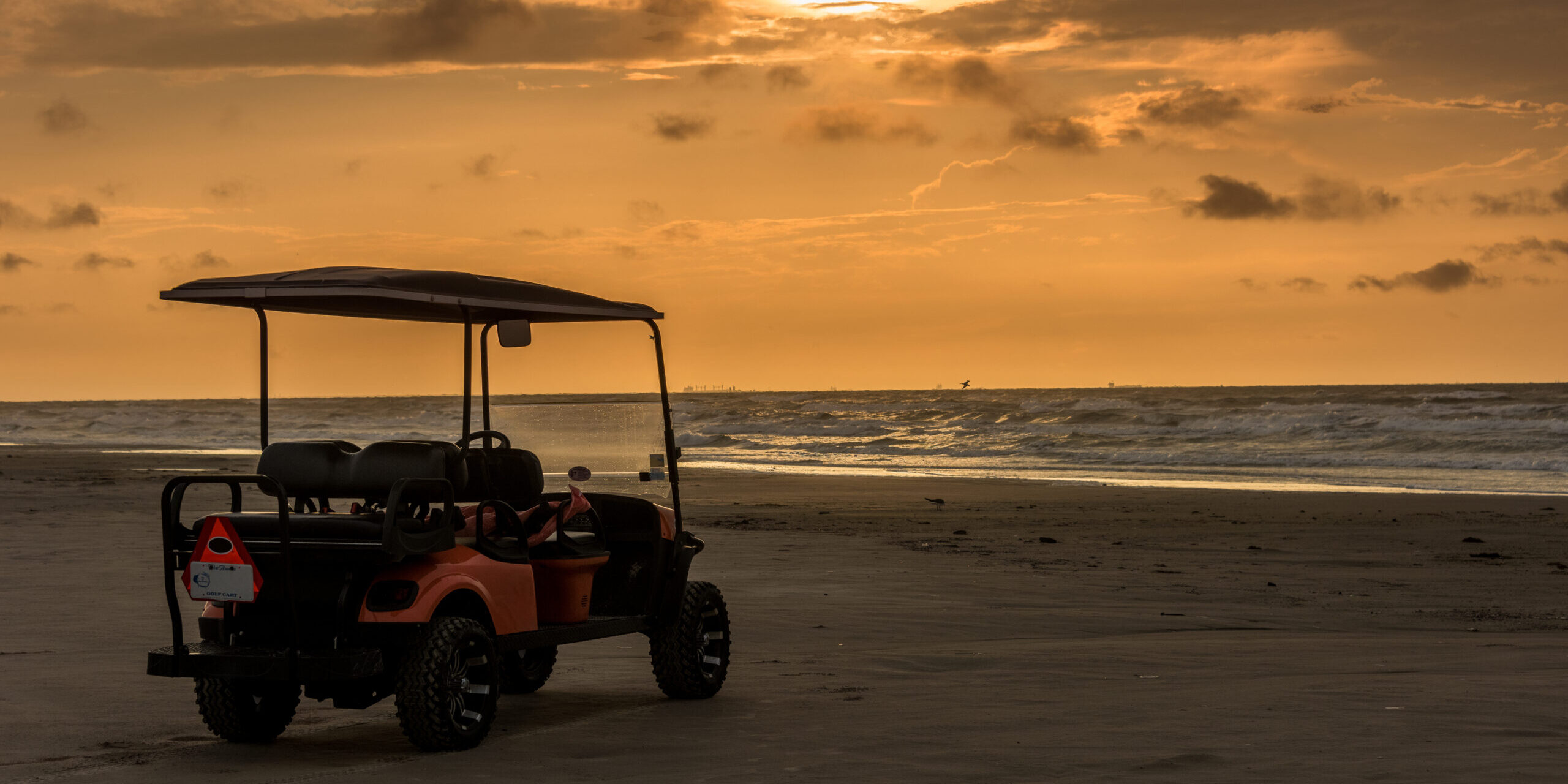 Golf cart parked on beach near sunset in Port Aransas, Texas